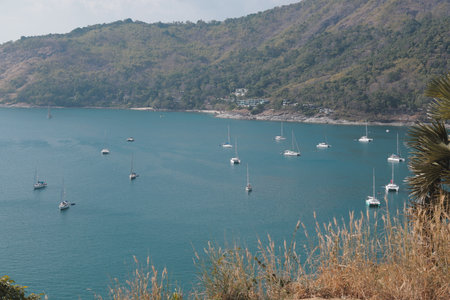 A picturesque scenic coastal view featuring sailing boats, rolling hills, and a beautiful skyの写真素材