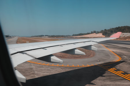 A Stunning View of an Airplane Wing While Taxiing Along the Runway at the Airportの写真素材