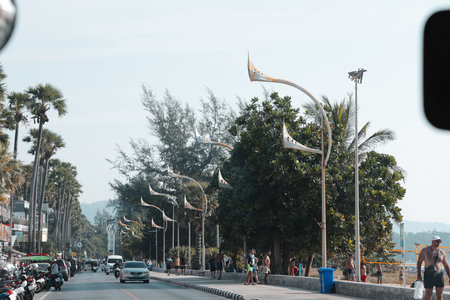 Enjoy a picturesque view of a scenic coastal road adorned with palm trees and decorative lightsの写真素材