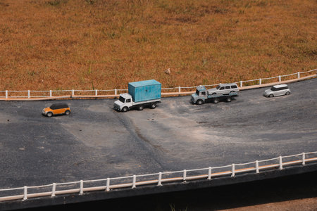 A Detailed Miniature Scene Featuring Various Vehicles Traveling Along a Curved Roadwayの写真素材