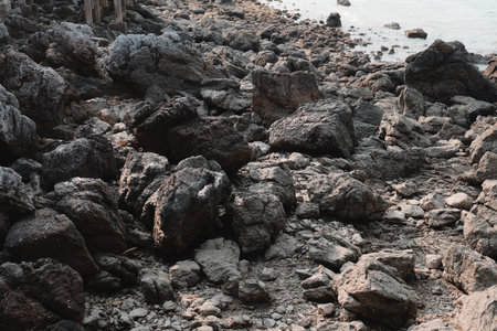 A Stunning Rocky Shoreline Featuring Beautifully Textured Stones and Gentle Water Wavesの写真素材