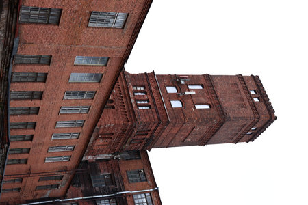 This is a historic red brick industrial building that features a tall tower on its designの写真素材