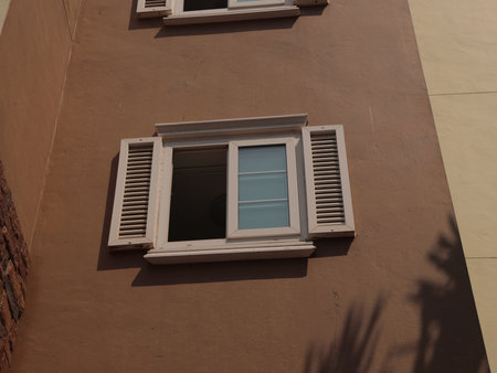 Charming and Inviting Window with Decorative Shutters Set Against a Soft Beige Wall