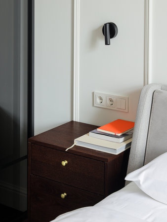 A modern nightstand with books and a stylish lamp in a minimalist bedroom highlighting eleganceの写真素材