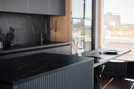 Discover a Stunning Modern Kitchen Design Featuring Sleek Black Finishes and an Elegant Dining Areaの写真素材