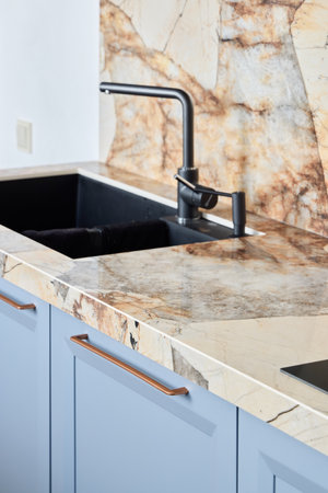A modern kitchen sink has an elegant marble countertop and stylish faucet, enhancing its lookの写真素材
