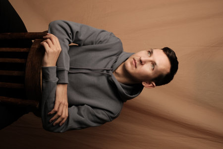 A Reflective Young Man, Dressed in Casual Attire, is Sitting Comfortably and Relaxed on a Chairの写真素材