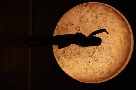 Silhouette Dance Against a Big, Bright Moon in the Night Sky, Creating an Ethereal Sceneの写真素材