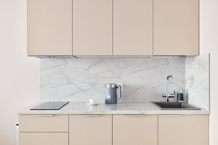 This modern minimalist kitchen has a marble backsplash and neutral cabinets for eleganceの写真素材