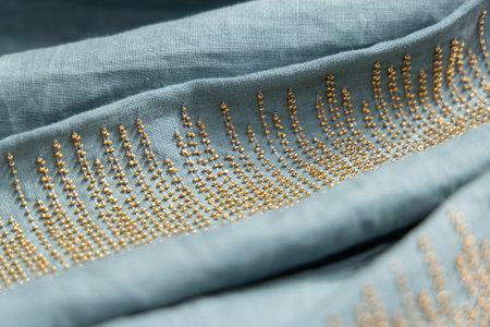 This elegant blue fabric is adorned with intricate and stunning golden embroidery details