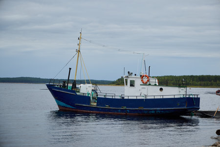 A Beautiful Fishing Boat Gracefully Docked at the Tranquil, Calm Waters Beneath a Cloudy Skyの写真素材