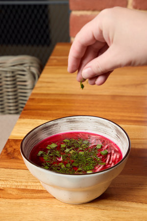 Garnishing a Deliciously Vibrant Beet Soup with a Variety of Fresh, Flavorful Herbs