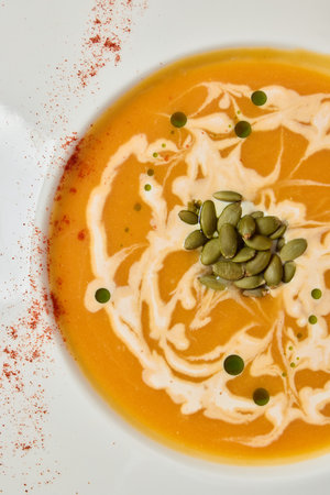 Enjoy a creamy Pumpkin Soup topped with seeds and swirls for a delightful autumn flavorの写真素材