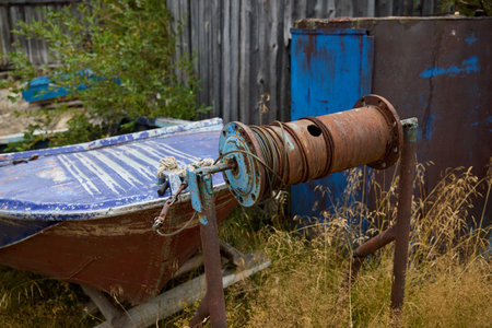 An Abandoned Fishing Gear Featured with a Rusty Winch and Old Boat in a Coastal Settingの写真素材