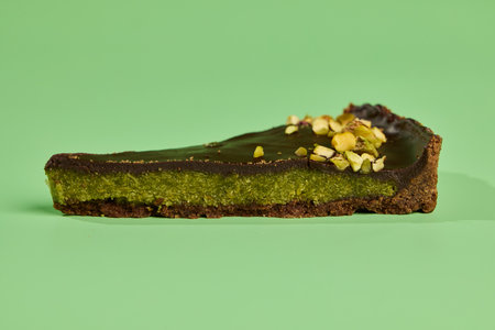 Enjoy a Pistachio Chocolate Tart Slice beautifully displayed on a vibrant green background