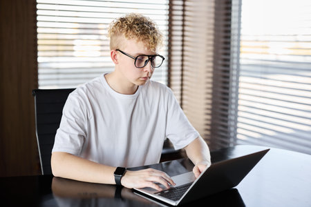 A young man is using a laptop in a stylish and functional modern setting
