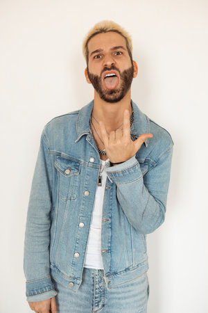 A man making a punk gesture in a stylish denim outfit that highlights his individualityの写真素材