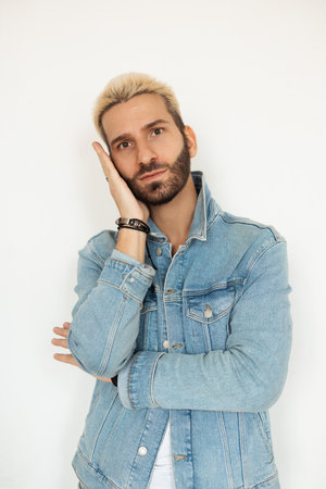 A Stylish Young Man in a Denim Jacket Posing Thoughtfully with a Cool Attitude and Confidence