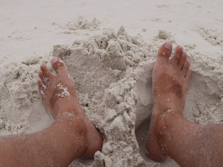 A Relaxing Beach Scene Featuring Soft Sand and Tranquil Feet in the Warm Sunshineの写真素材