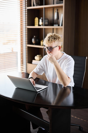 A focused young professional diligently working on a laptop in a modern, stylish office environmentの写真素材