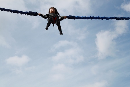 Little girl jumping on the trampoline  bungee jumping  の写真素材