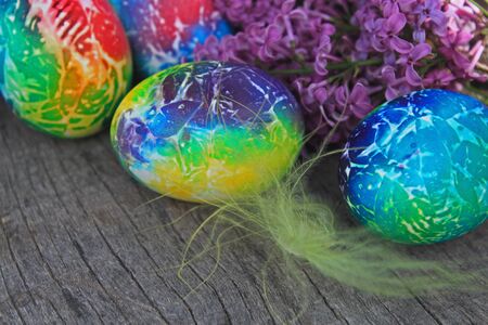 Easter background. Art painted eggs with lilac and feather on wooden background.の写真素材