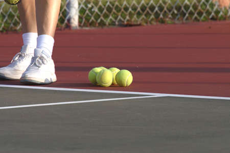 Tennis court with lady standing by tennis ballsの写真素材