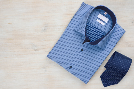 Folded blue man shirt and tie isolated on wooden backgroundの写真素材