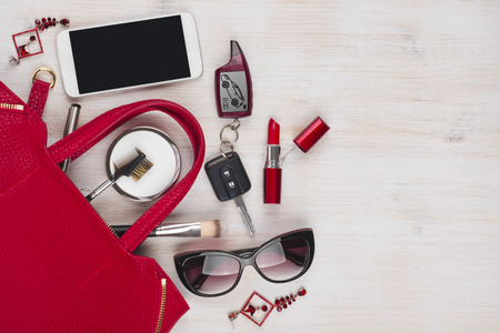 Female things and red handbag on wooden background with copyspaceの写真素材