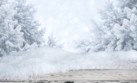 Wooden table with snowdrifts over blurred abstract winter landscape backgroundの写真素材