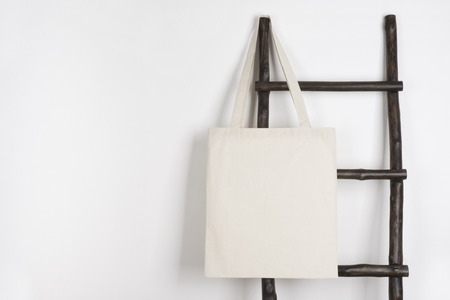 Fabric cloth shopping bag mockup hanging on vintage wooden stepladderの写真素材