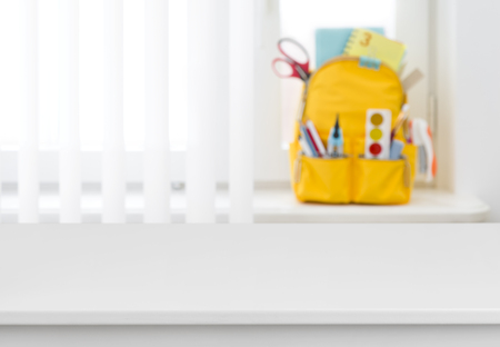 White table over blurred background of school backpack on windowの写真素材
