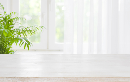 Wooden table top on blurred  of half curtained windowの写真素材