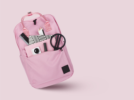 School backpack with various stationery tools isolated on pinkの写真素材