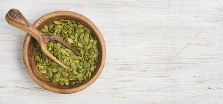 Pumpkin seeds in wooden spoon and bowl on vintage backgroundの写真素材