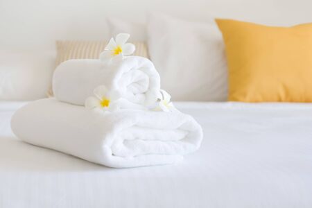 Clean white spa towels and flowers in blurred bedroom interiorの写真素材