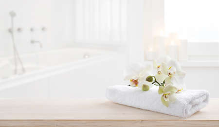 White folded spa towel and orchid flowers on wooden tableの写真素材