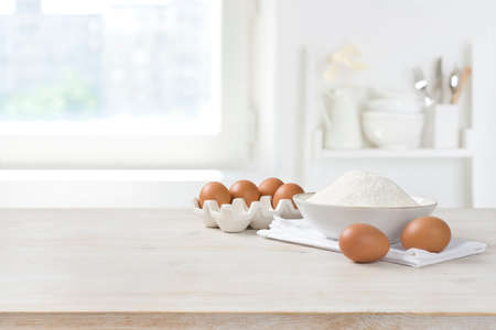 Baking ingredients on wooden table over defocused kitchen window backgroundの写真素材