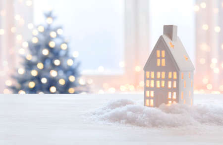 Glowing Christmas lantern of house shape on blurred holiday backgroundの写真素材