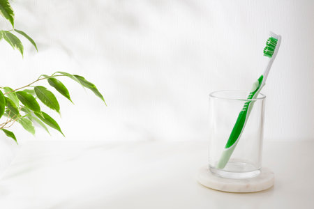 Glass holder on marble stand with toothbrush on white backgroundの写真素材