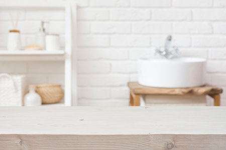 Empty wooden table and blurred view of bathroom sink interiorの写真素材