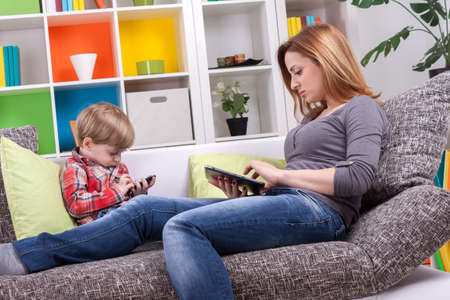 Mother and little boy playing with tablet and phone の写真素材