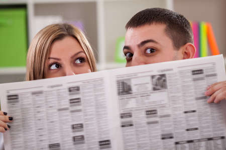 Couple peeping behind a newspaperの写真素材