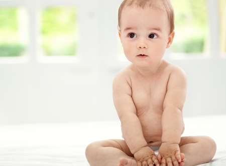 Little baby thinker sitting on bedの写真素材