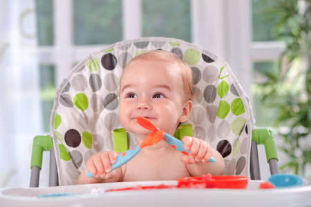 Beautiful  baby holding itself with a spoon and forkの写真素材