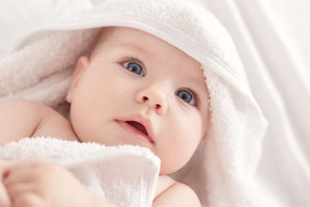 Cute baby with blus eyes under the white towel