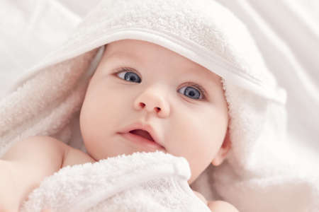 Baby after bath under white towelの写真素材