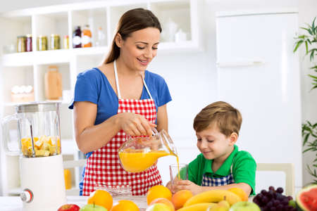 Young mother and child prepare fruits juice in kitchenの写真素材