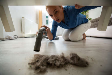 Surpriced blonde housewife find dust under furnitureの写真素材