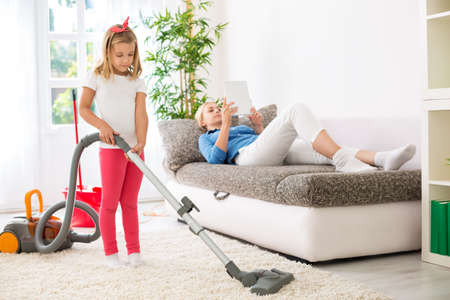 Lazy mother exploitation little child for cleaning homeの写真素材